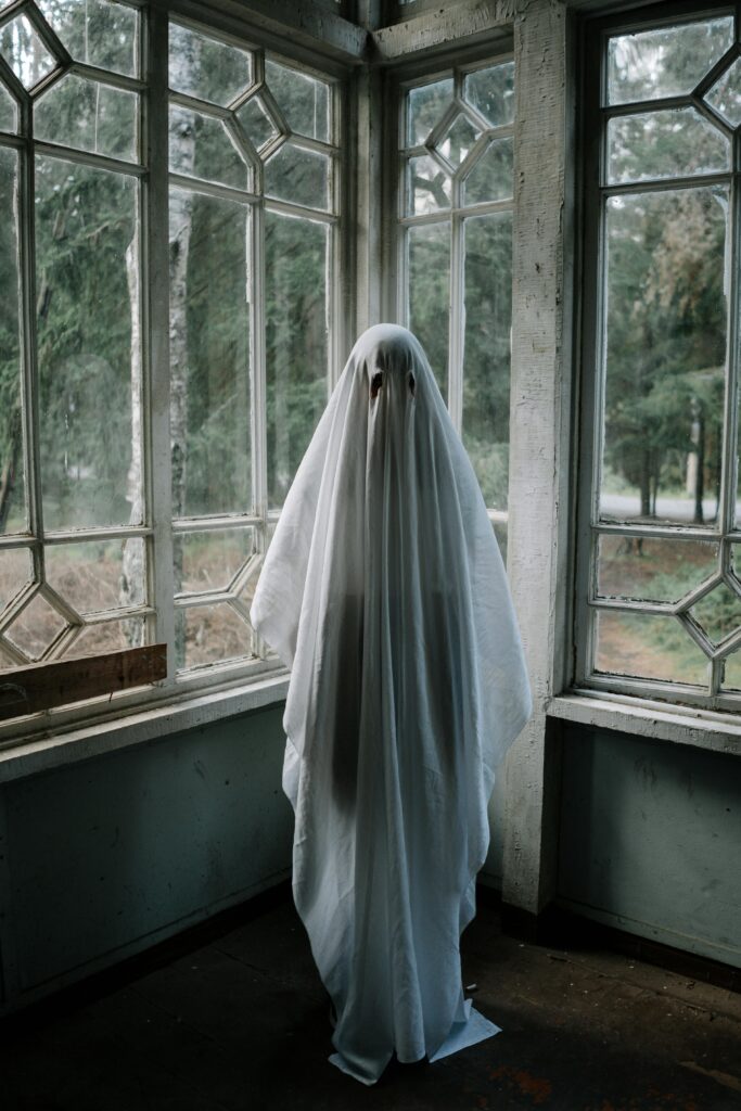 Eerie ghostly figure in a white sheet inside an abandoned house, evoking Halloween vibes.